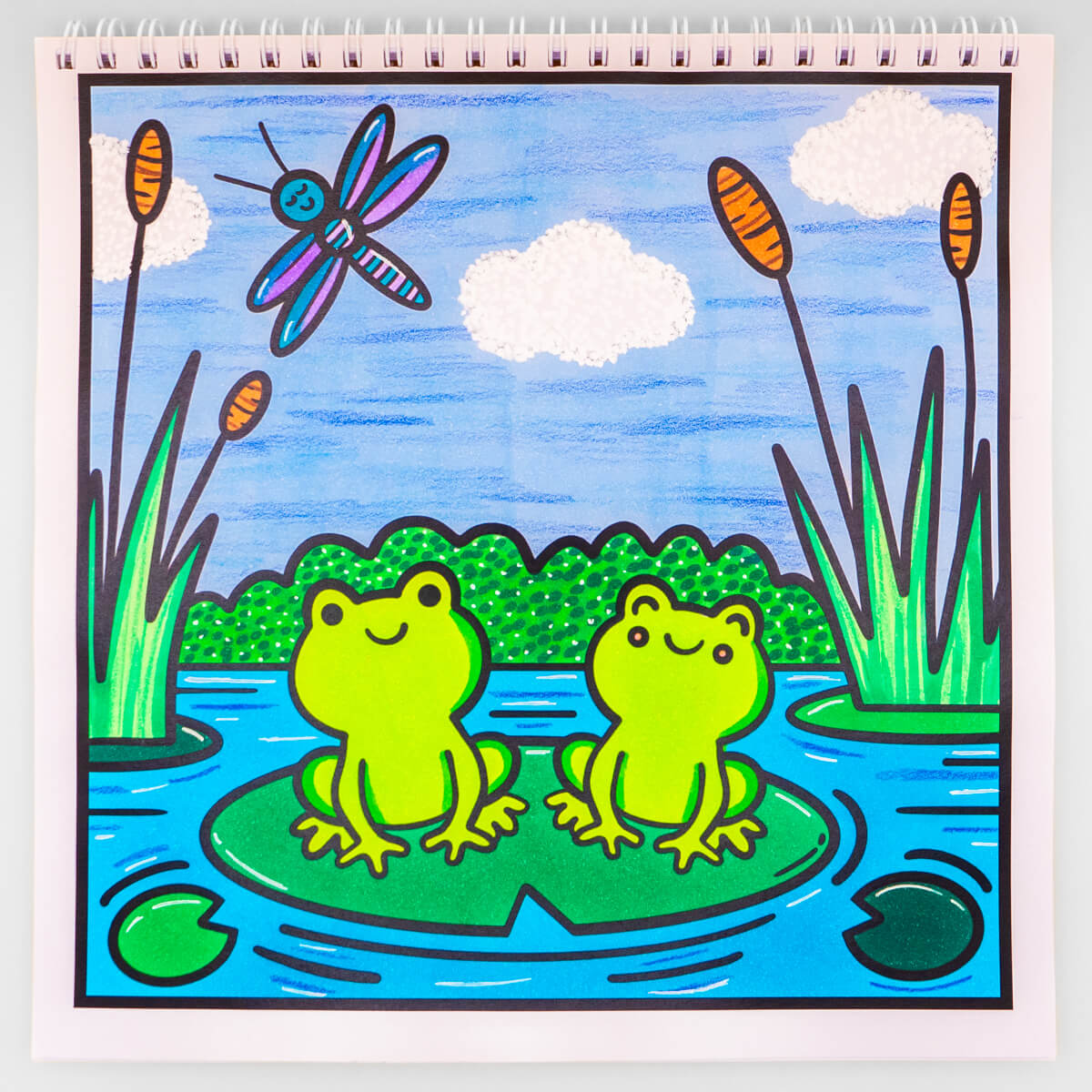 Cute frog pond colouring page with lily pads, dragonflies, and cattails, designed for creative colouring fun.