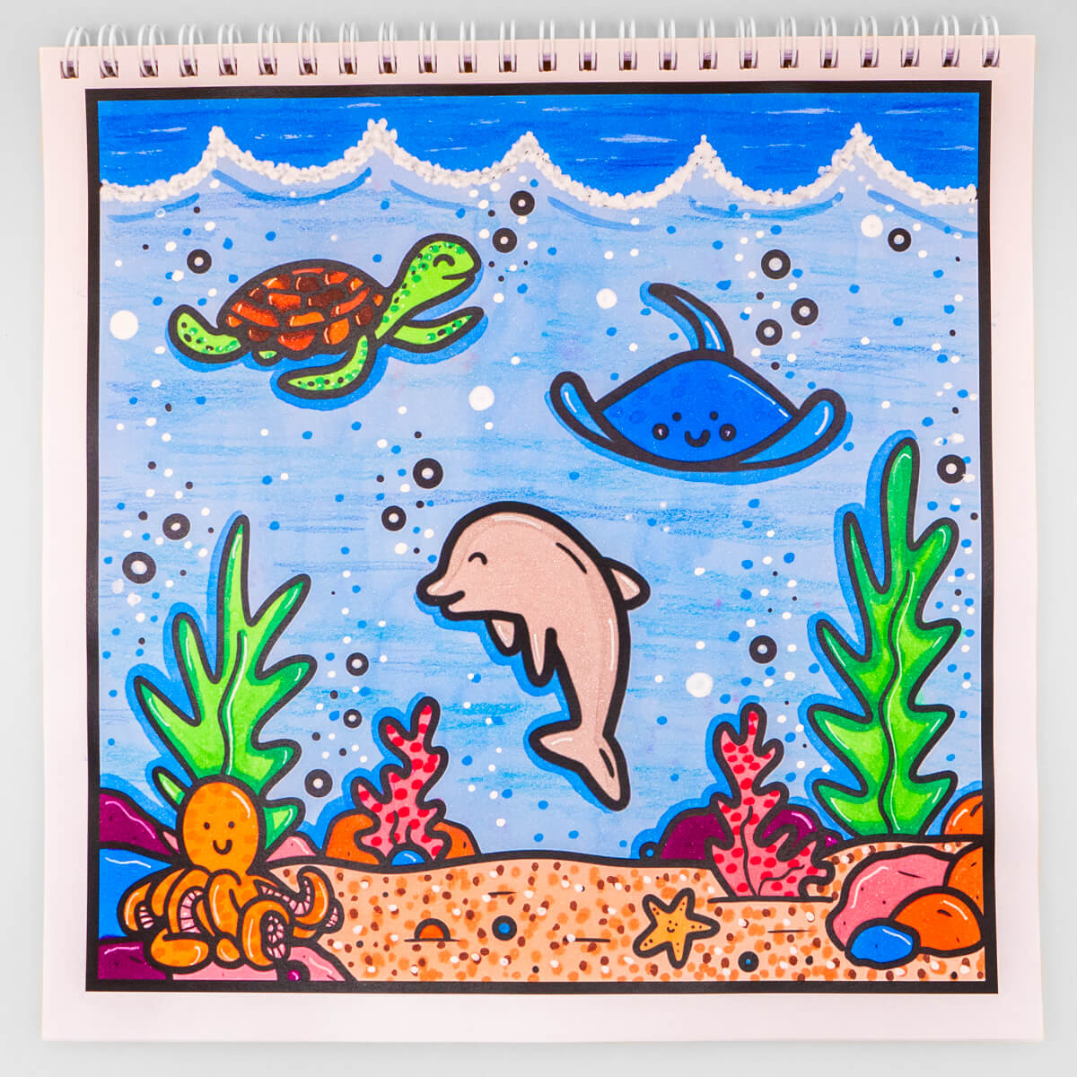 A vibrant ocean-themed colouring page featuring a playful dolphin, smiling turtle, friendly stingray, and a cute octopus surrounded by coral, seaweed, and bubbles. Perfect for creative colouring fun.